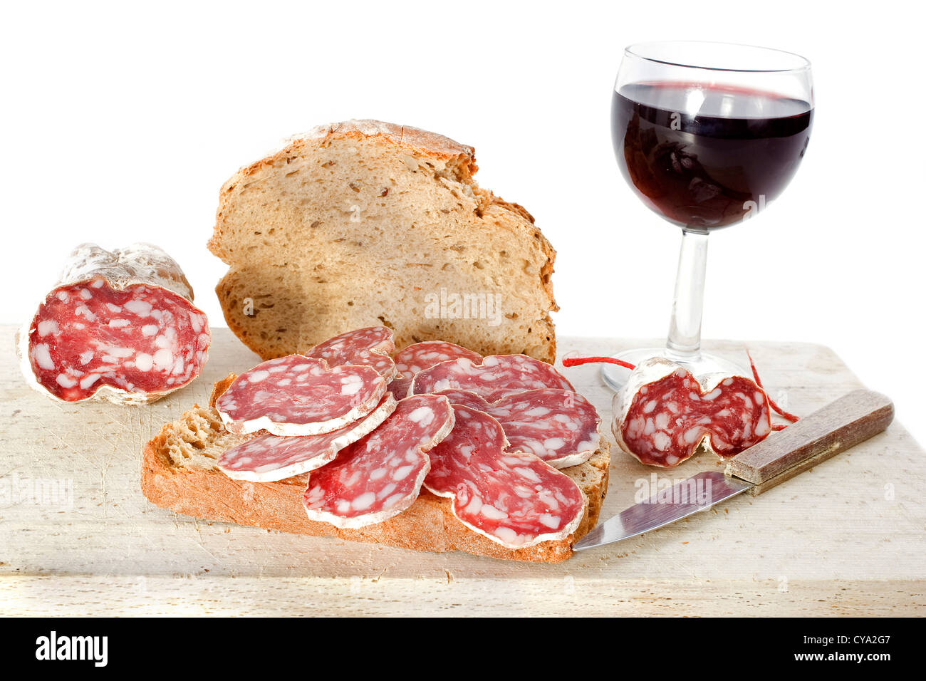 Fette di salsiccia francese sul pane con coltello, vino e pane di fronte a uno sfondo bianco Foto Stock