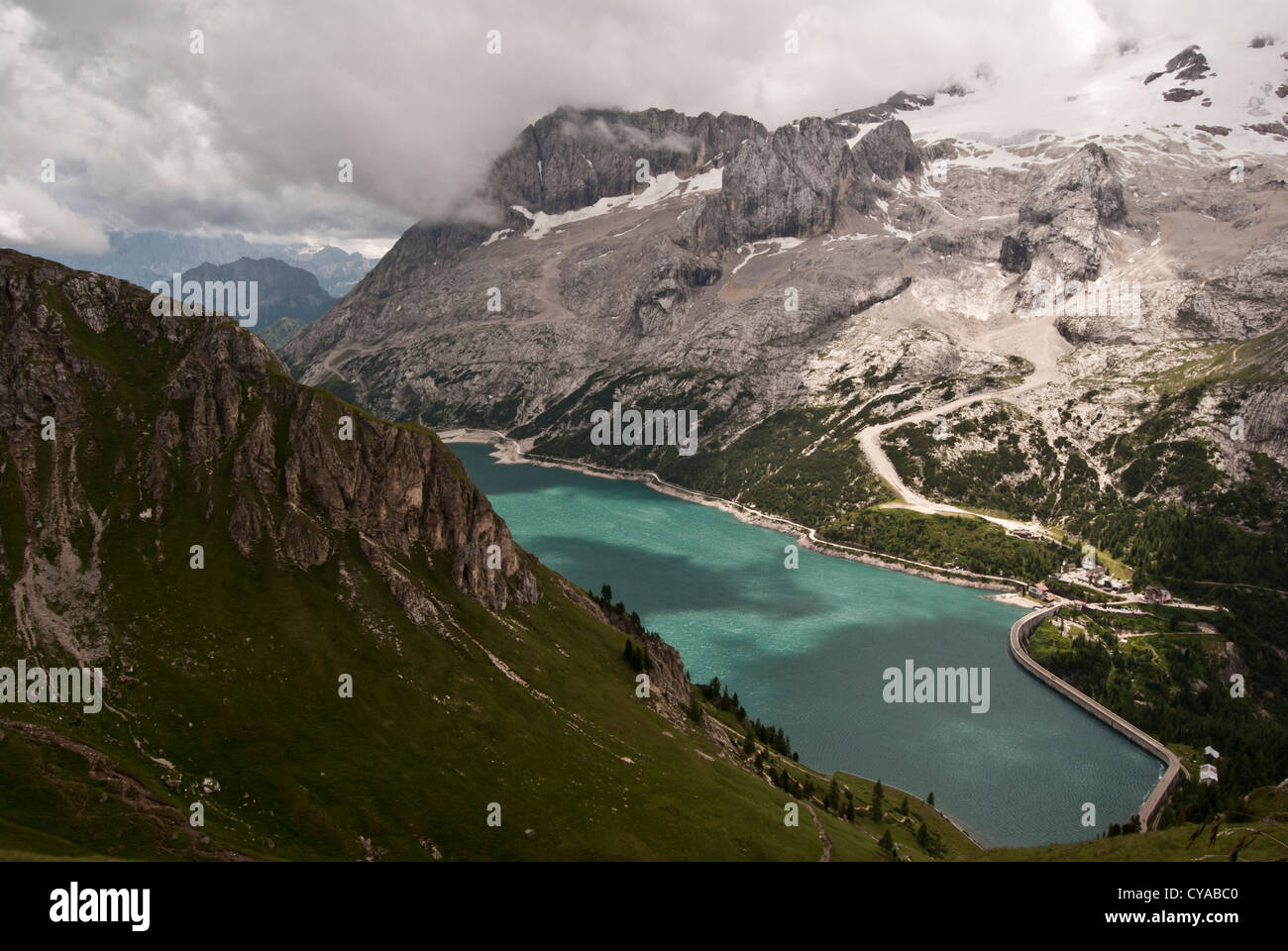 Lago di Fedaia serbatoio di acqua con la Marmolada cresta di montagna con il ghiacciaio in Dolomiti in Italia durante la giornata estiva con cielo blu e nuvole Foto Stock