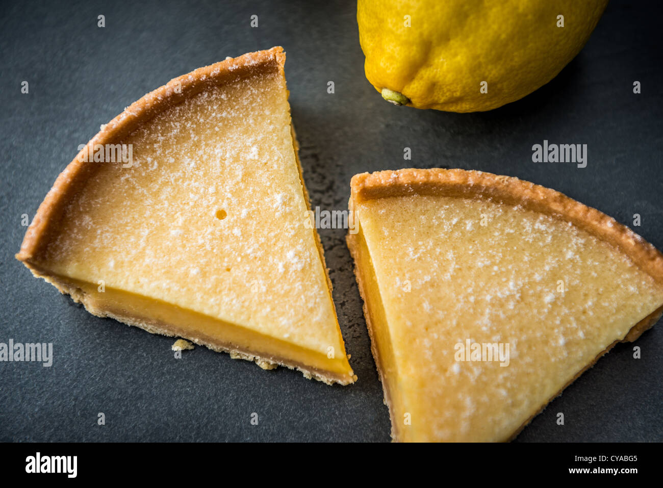 Crostata al limone dessert a base di biscotto sulla superficie di ardesia con limoni in background shot dal di sopra Foto Stock