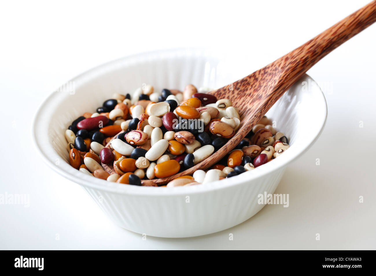 Miscelati chicchi crudi o legumi con un cucchiaino di noce di cocco in una ciotola Foto Stock