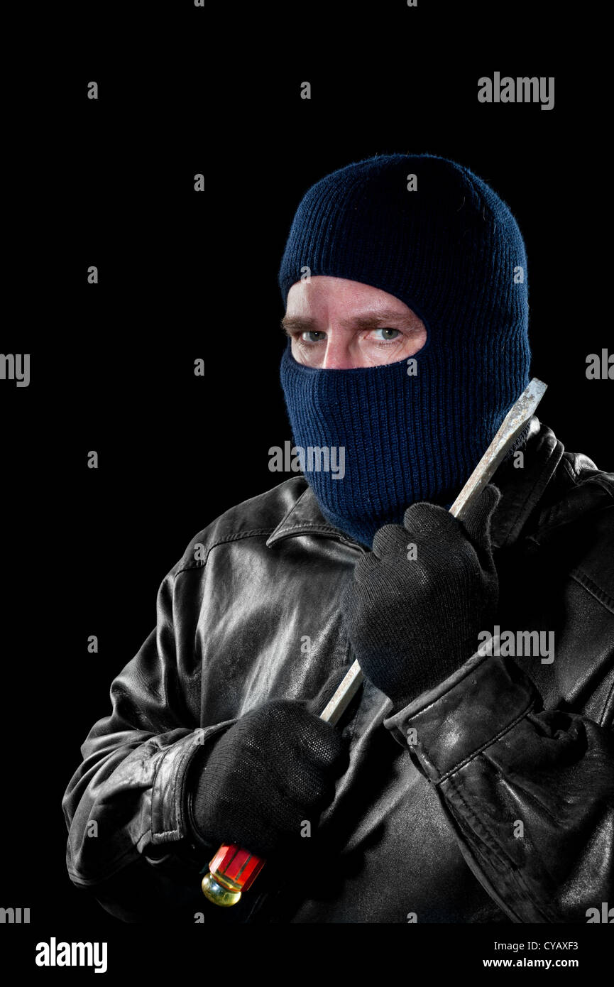 Un ladro criminale in una maschera da sci per nascondere la propria identità detiene un cacciavite grande come egli ha preparato per commettere un crimine. Foto Stock