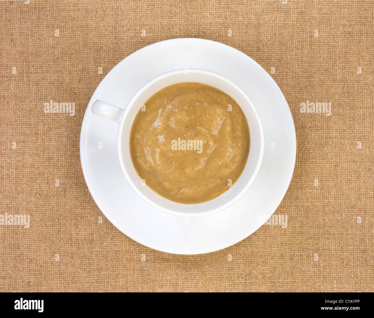 Vista dall'alto di un antiossidante della bevanda in una tazza bianca con piattino su un panno marrone chiaro dello sfondo. Foto Stock
