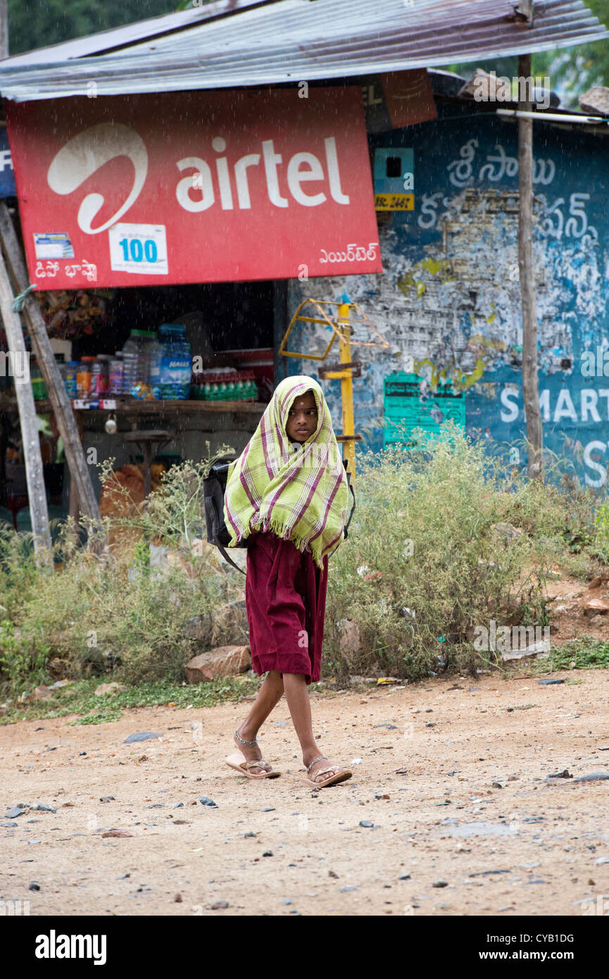 Indian School ragazza camminare sotto la pioggia a una fermata di autobus. Andhra Pradesh, India Foto Stock