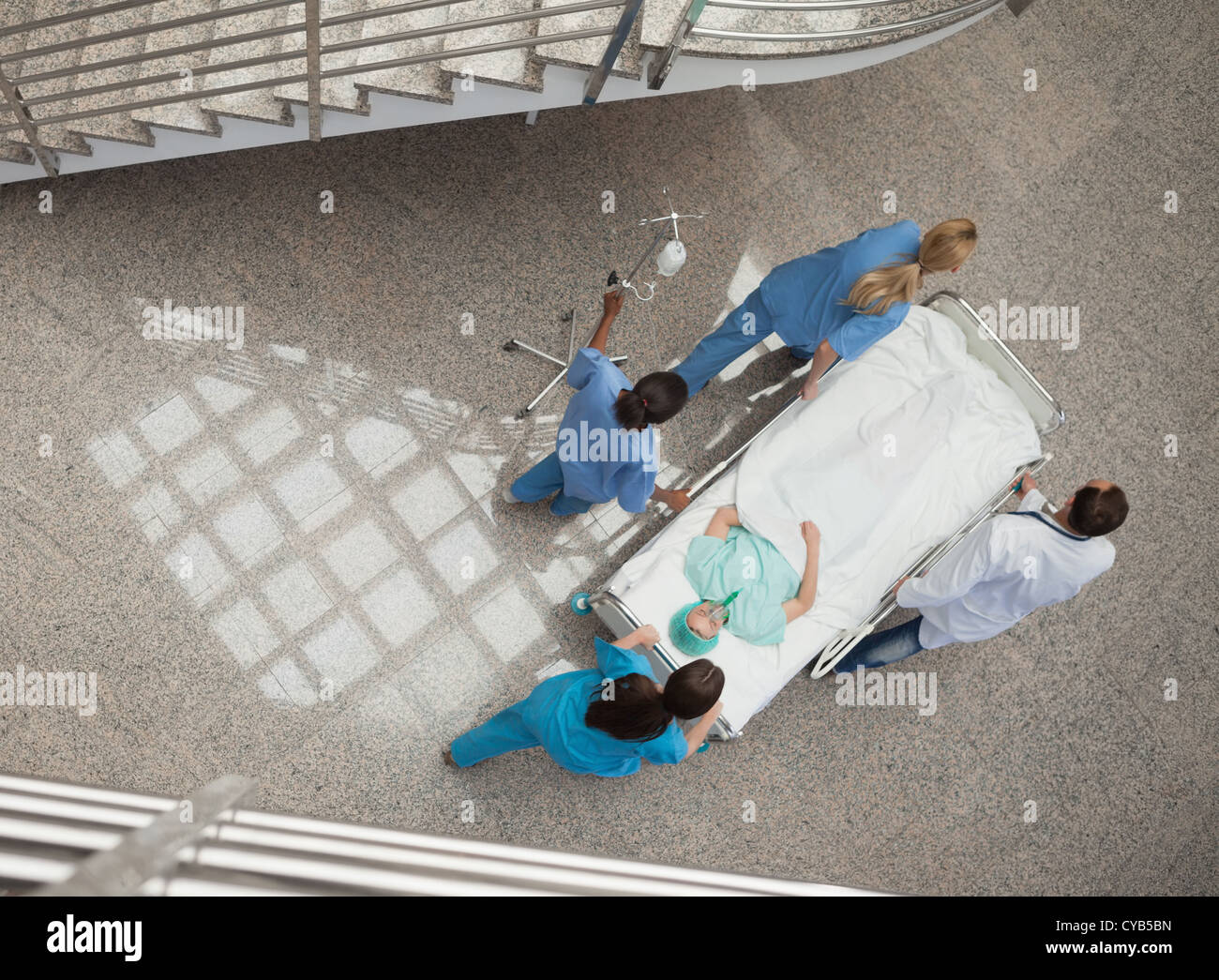 Tre Infermieri e un medico spingendo un paziente in una barella Foto Stock