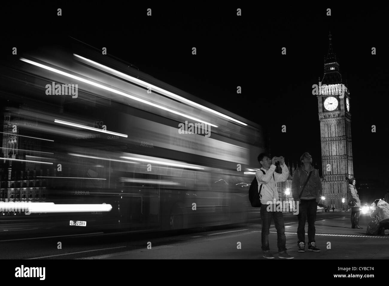 Una vista notturna di Westminster Bridge tra cui il Big Ben, persone e un double decker rosso London bus Foto Stock