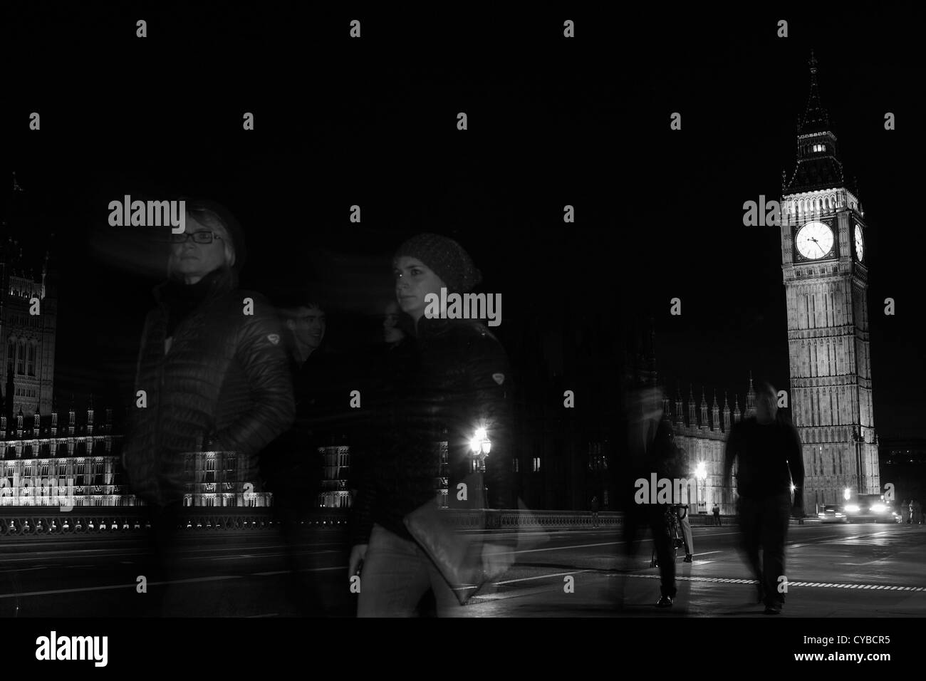 La gente che camminava sul Westminster Bridge, Londra, durante la notte con le case del Parlamento a distanza Foto Stock