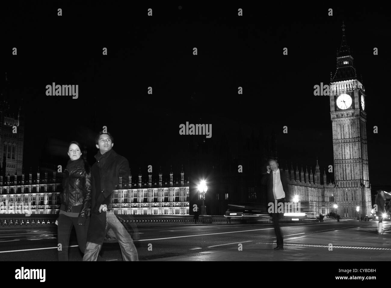 La gente che camminava sul Westminster Bridge, Londra, durante la notte con le case del Parlamento a distanza Foto Stock
