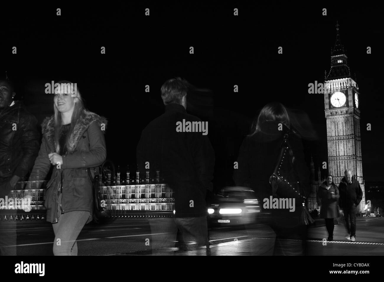 La gente che camminava sul Westminster Bridge, Londra, durante la notte con le case del Parlamento a distanza Foto Stock