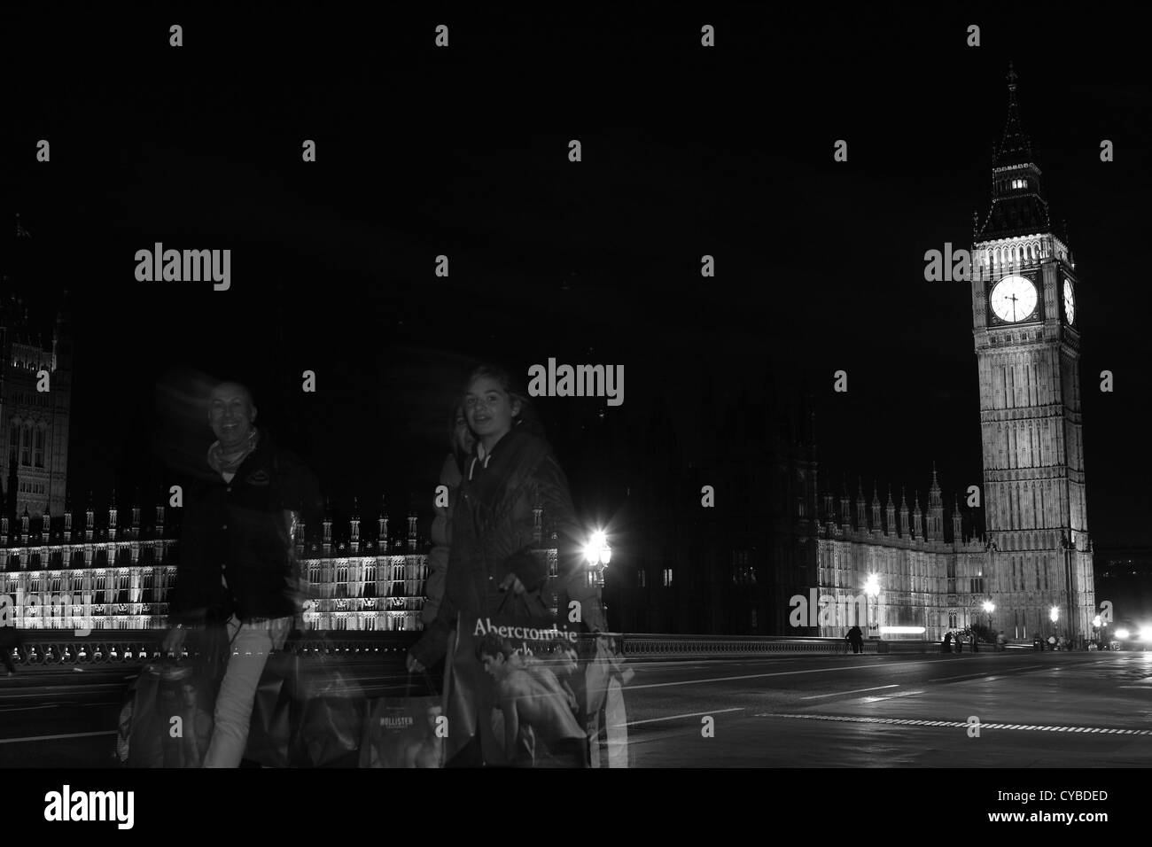 La gente che camminava sul Westminster Bridge, Londra, durante la notte con le case del Parlamento a distanza Foto Stock