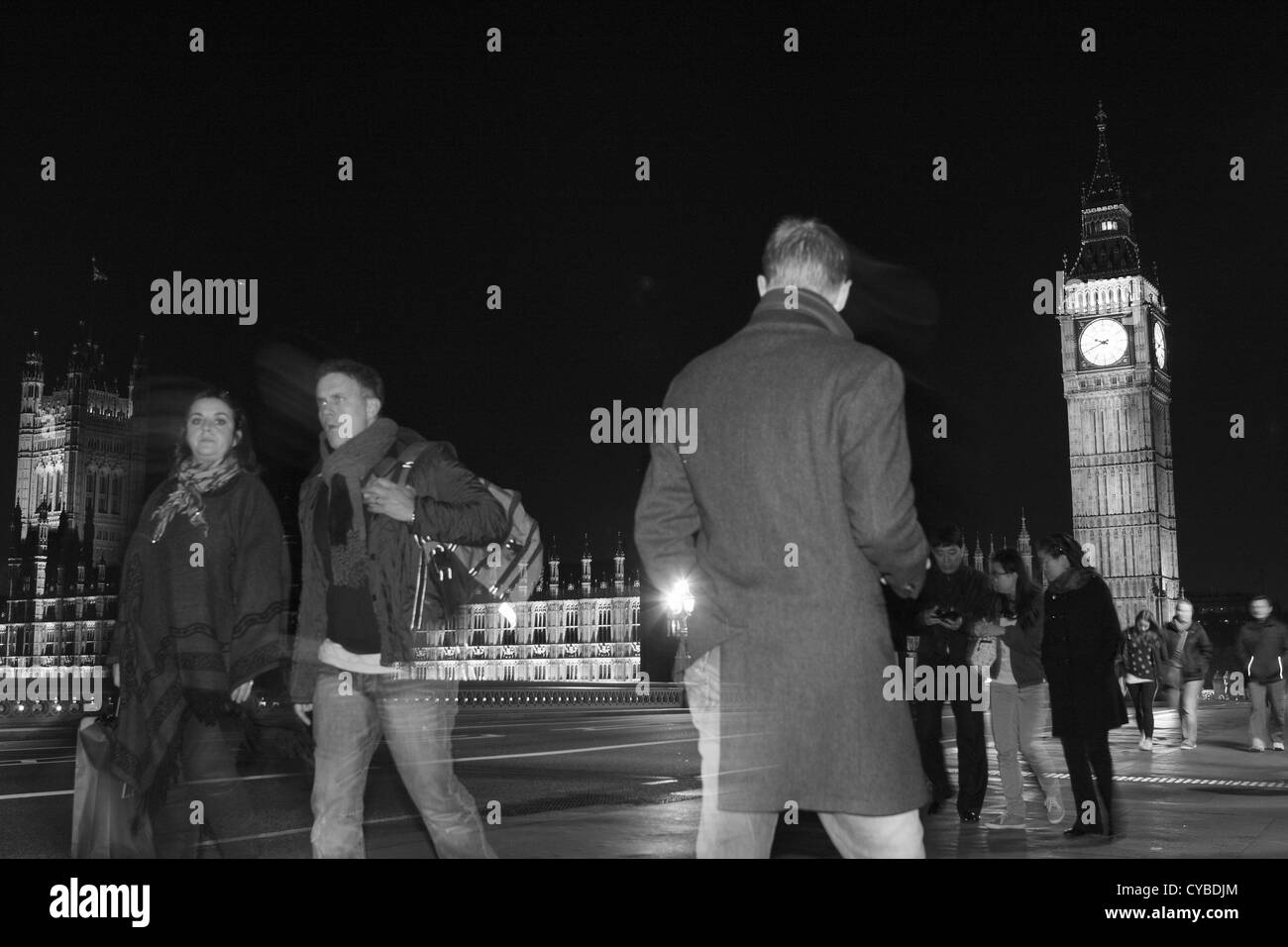 La gente che camminava sul Westminster Bridge, Londra, durante la notte con le case del Parlamento a distanza Foto Stock