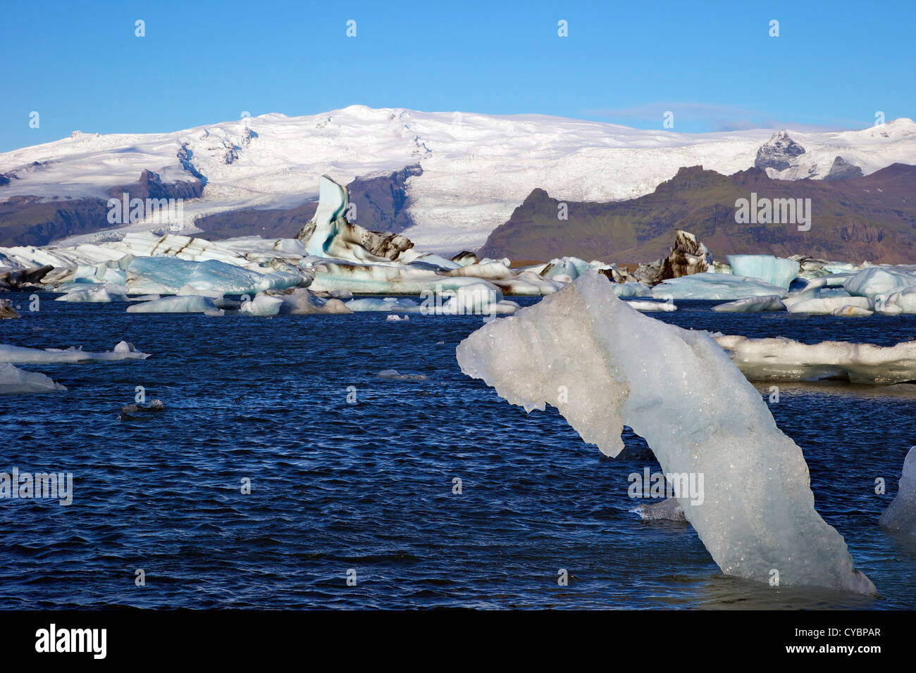 Iceberg su un lago glaciale a Jokulsarlon con neve sul massiccio del icecap Vatnajokull dietro, Islanda Foto Stock