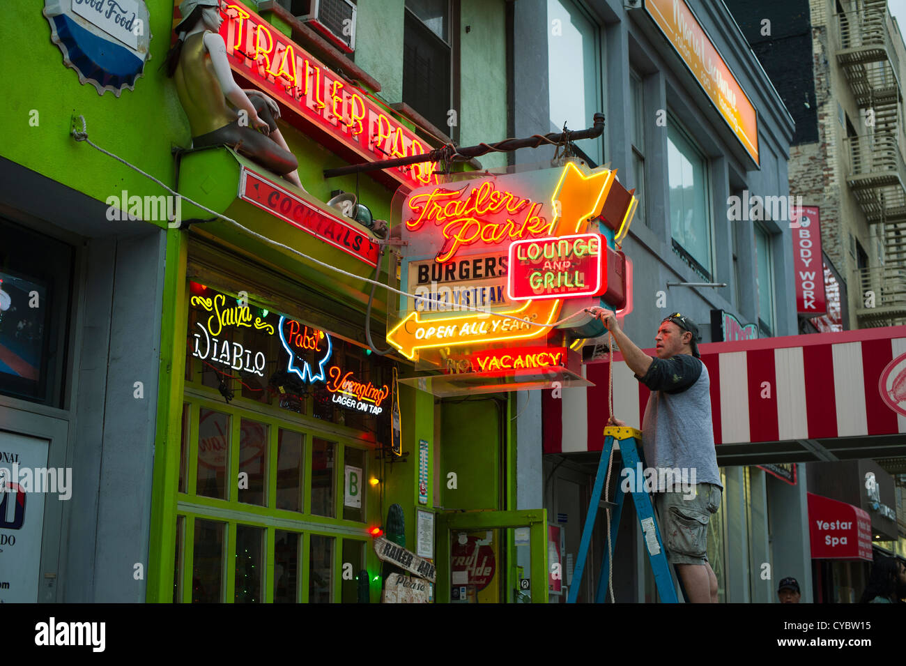 Un uomo fissa un ristorante al neon segno prima di un uragano Sandy nel quartiere di Chelsea di New York Foto Stock