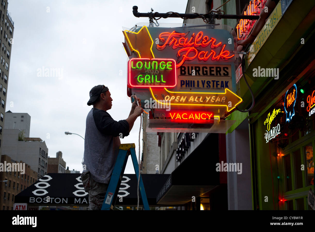 Un uomo fissa un ristorante al neon segno prima di un uragano Sandy nel quartiere di Chelsea di New York Foto Stock