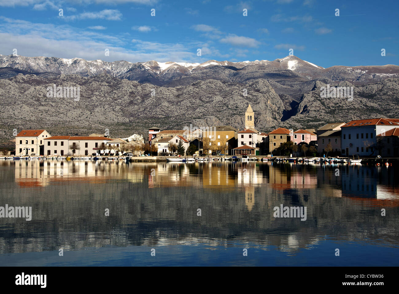 Piccola città costiera di Vinjerac in Croazia al mattino presto con mare calmo, riflessi in acqua e montagne sullo sfondo. Foto Stock