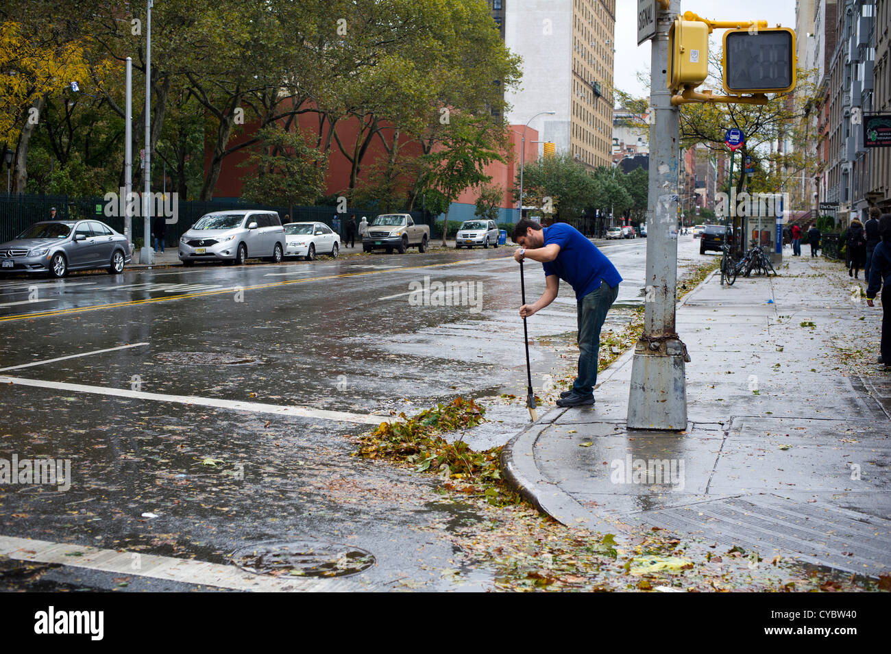 Un uomo che pulisce storm i detriti dai forti venti di uragano Sandy lontano da una tempesta scaricare visto in New York Foto Stock
