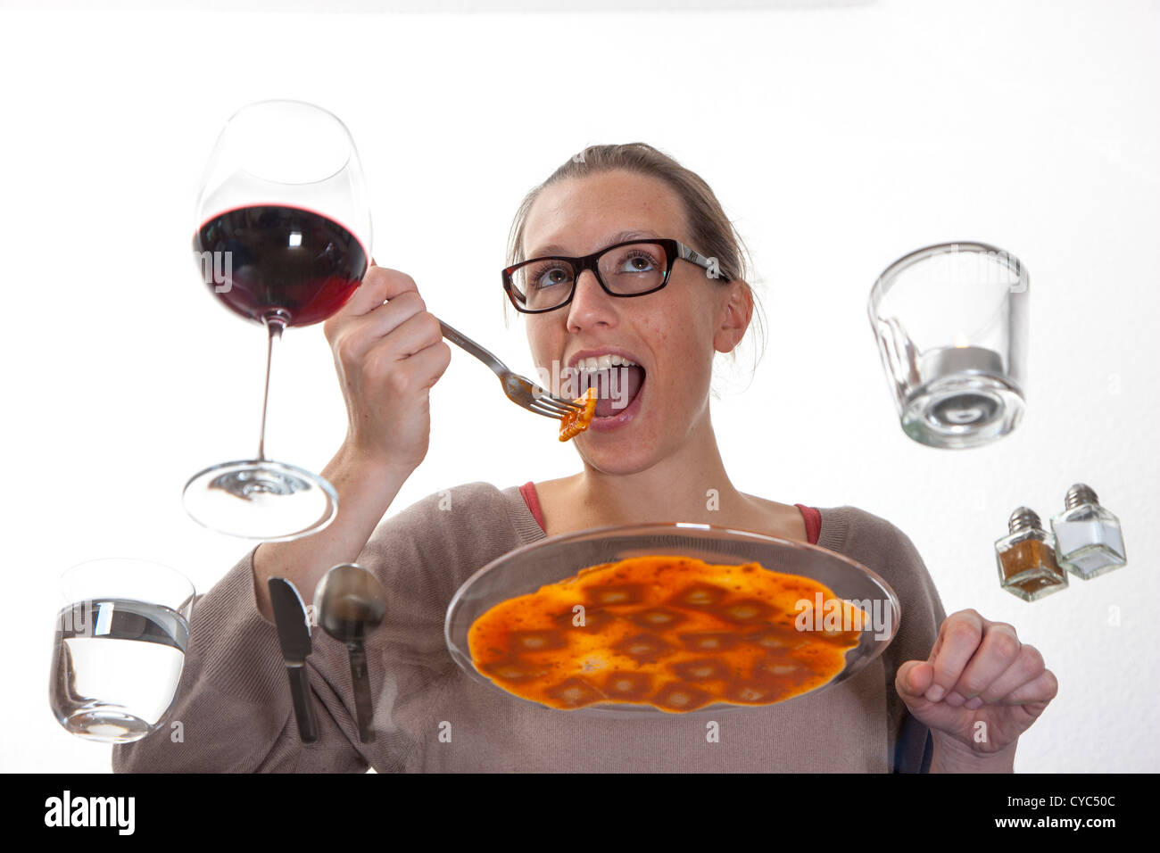 Giovane donna è seduta al tavolo di vetro. Mangiare pasta, ravioli con una salsa di pomodoro, acqua minerale e un bicchiere di vino rosso. Foto Stock