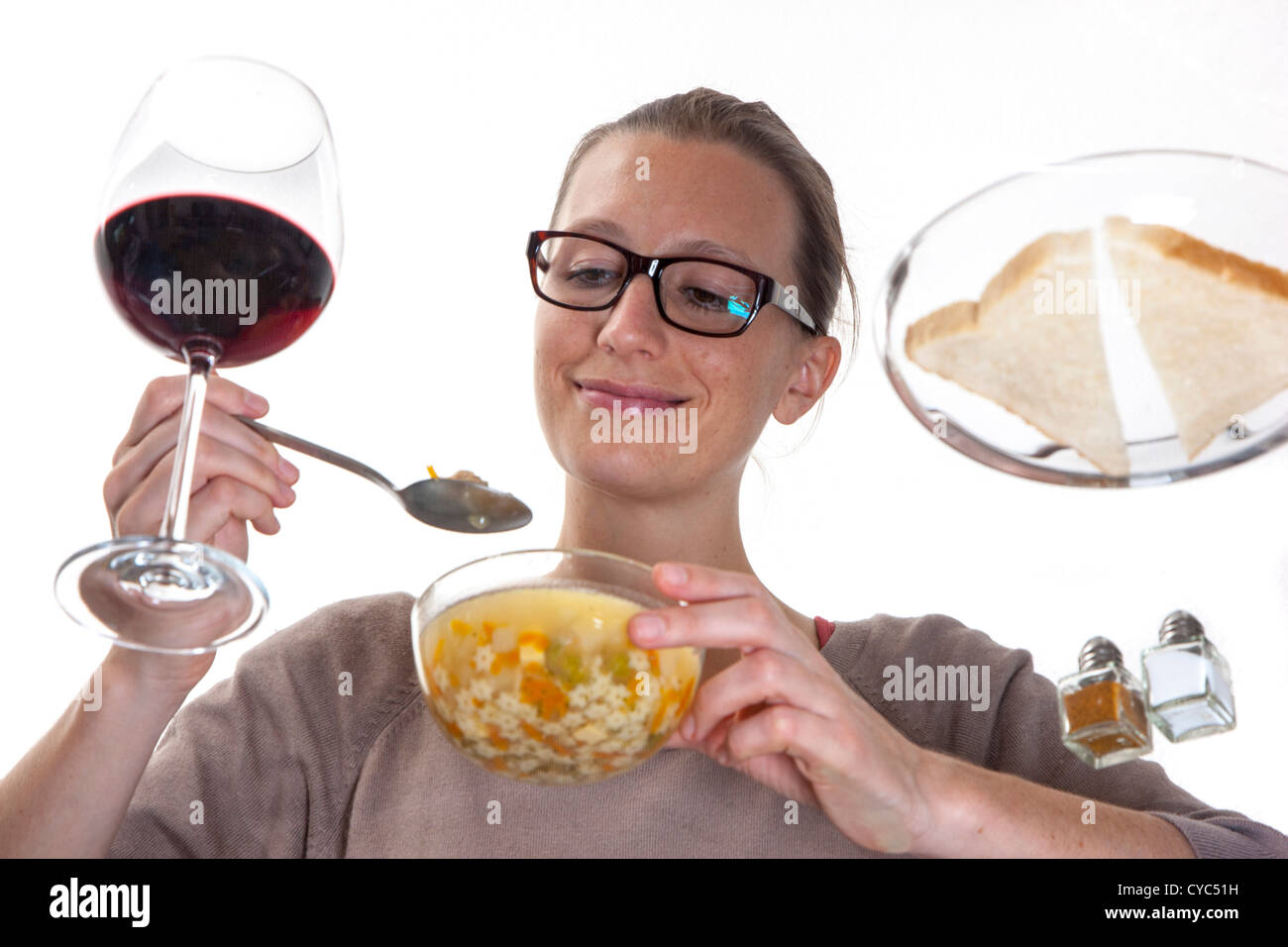 Giovane donna è seduta al tavolo di vetro, mangiare una zuppa di verdure, tagliatelle. Foto Stock