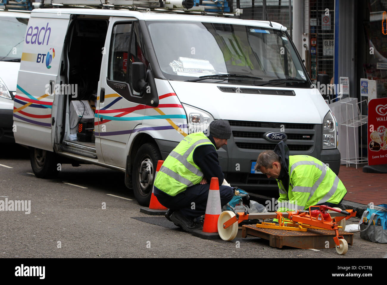 Due BT Openreach ingegneri lavoro raffigurato in un buco nel terreno in strada in Brighton, East Sussex, Regno Unito. Foto Stock