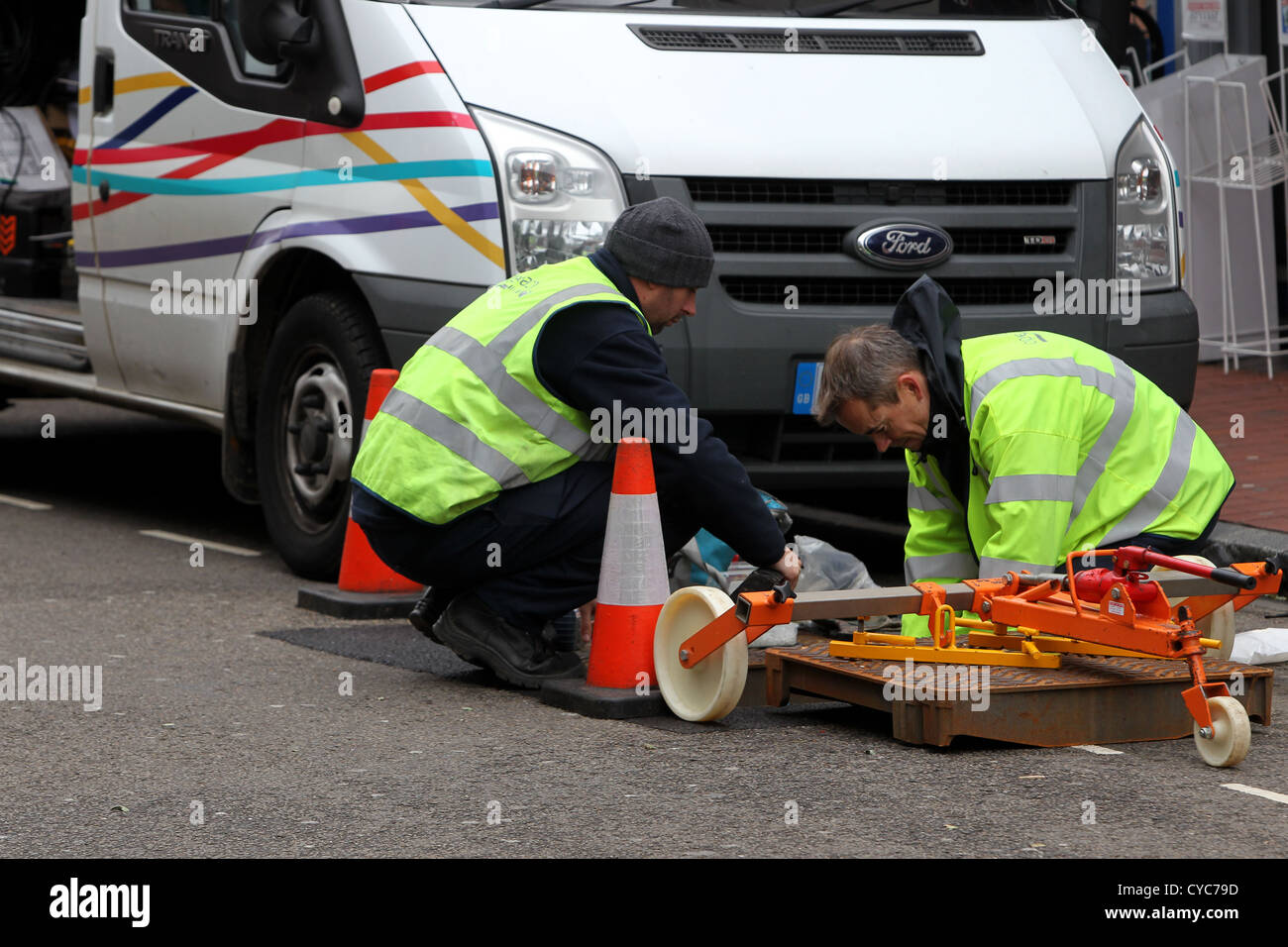 Due BT Openreach ingegneri lavoro raffigurato in un buco nel terreno in strada in Brighton, East Sussex, Regno Unito. Foto Stock
