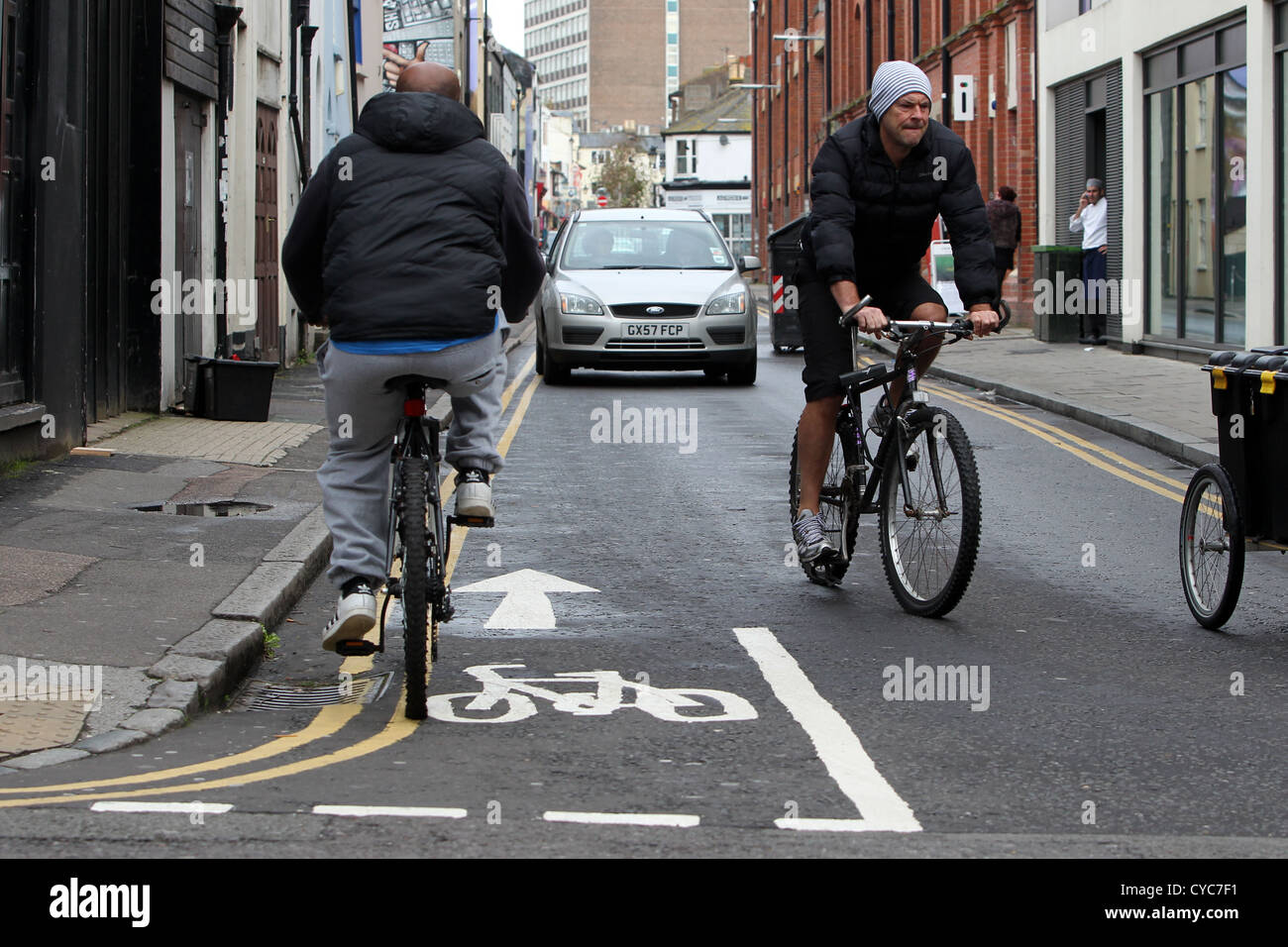 Ciclista in sella alla sua moto in una pista ciclabile fino a senso unico contro il flusso di traffico in Brighton, East Sussex, Regno Unito. Foto Stock