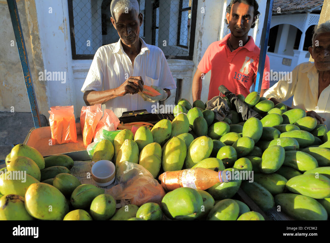 L'uomo vendita di manghi dal carrello di strada all'interno di Forte Galle, Sri Lanka. Foto Stock