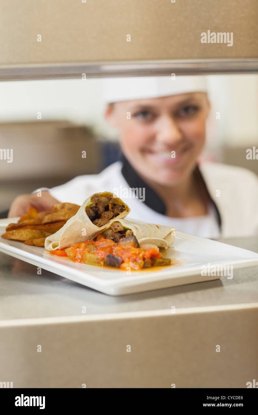 Allegro chef dando la piastra attraverso la stazione di ordine Foto Stock
