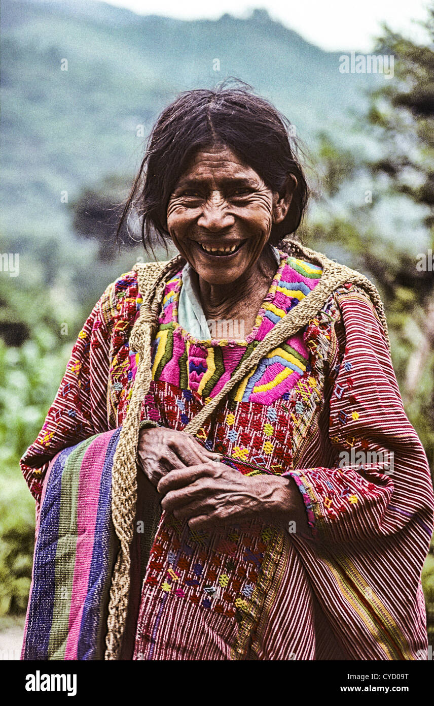 Anziani Mam vedova ampiamente sorridente e indossando il tradizionale intrecciato vestiti con i colori del suo villaggio, Acal, Guatemala. Foto Stock