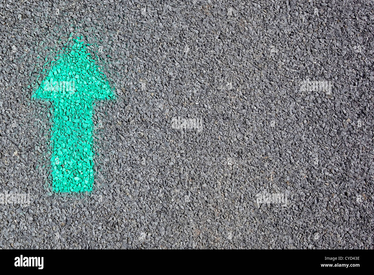 Immagine di sfondo di una freccia verde verniciato a spruzzo su di una strada asfaltata della superficie Foto Stock