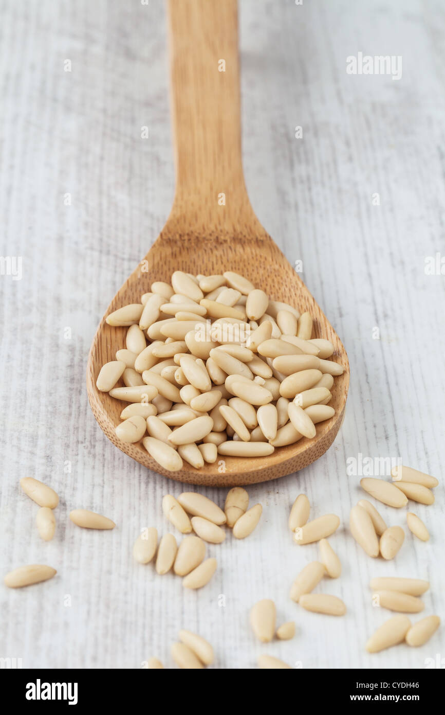 Crudo fresco pinoli su un cucchiaio di legno sul tavolo Foto Stock