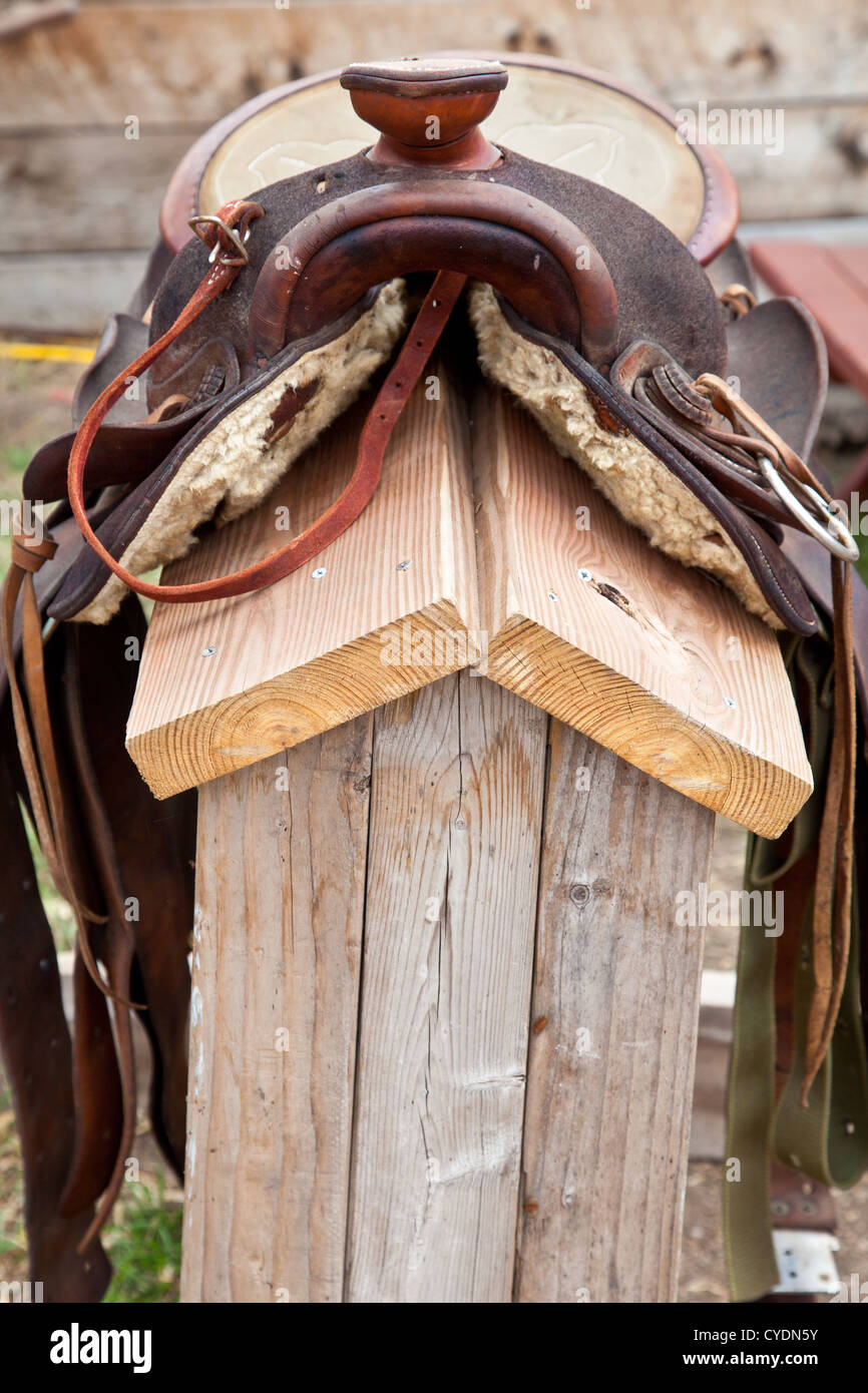 Una sella si siede su di una struttura di sella al di fuori di un fienile. Foto Stock