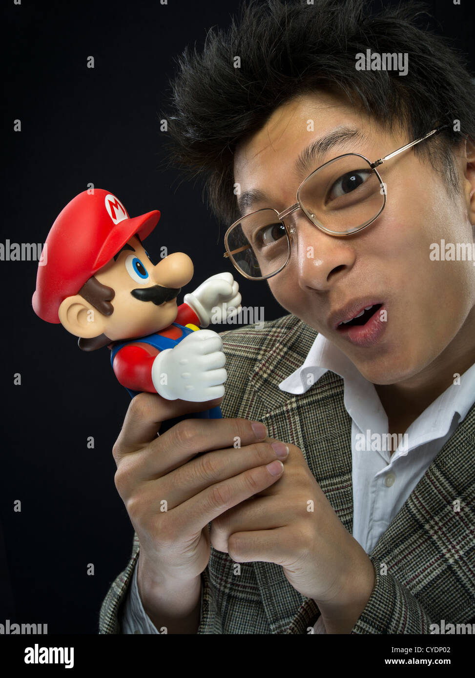 Geeky uomo asiatico con Super Mario doll / azione figura Foto Stock