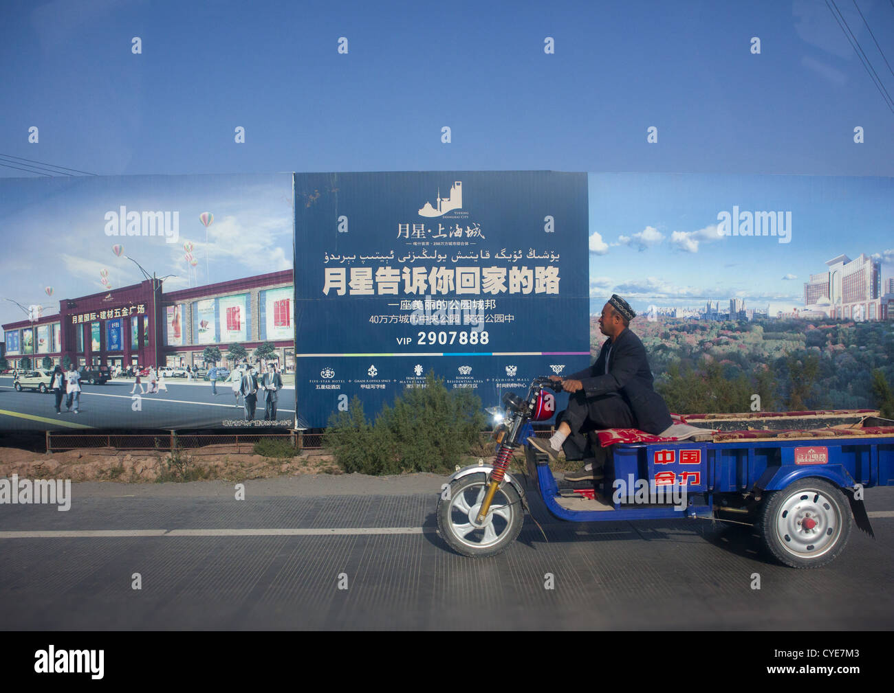 Il vecchio uomo passando di fronte la pubblicità per la nuova Immobiliare, Nuova città di Kashgar, Xinjiang Uyghur Regione autonoma, Cina Foto Stock