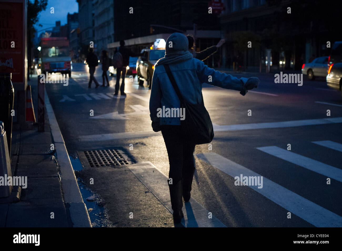 Quando scende la notte i newyorkesi ave cabs in corrispondenza di una intersezione a Chelsea a New York dalla luce dei fari di automobile Foto Stock