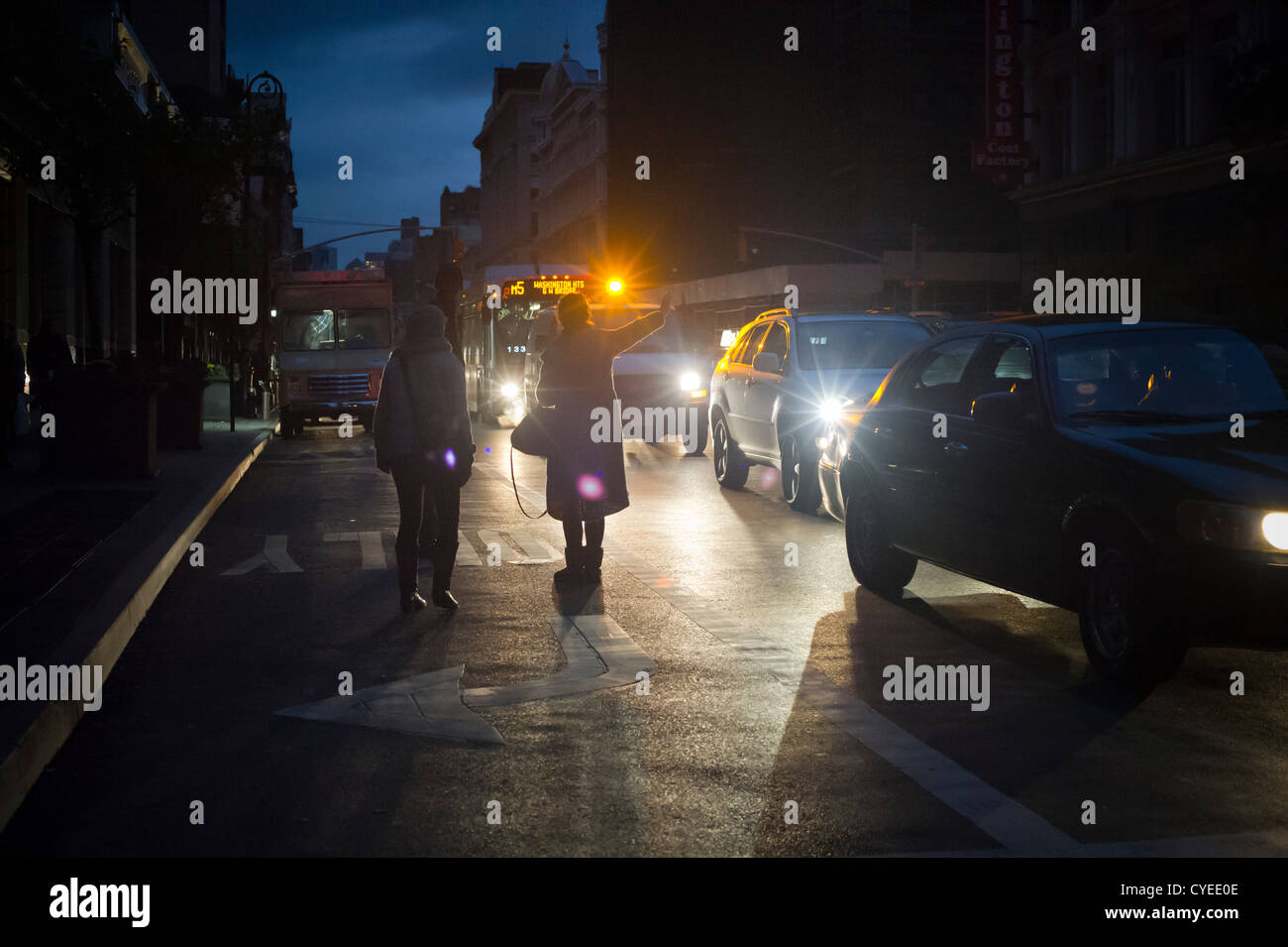 Quando scende la notte i newyorkesi ave cabs in corrispondenza di una intersezione a Chelsea a New York dalla luce dei fari di automobile Foto Stock