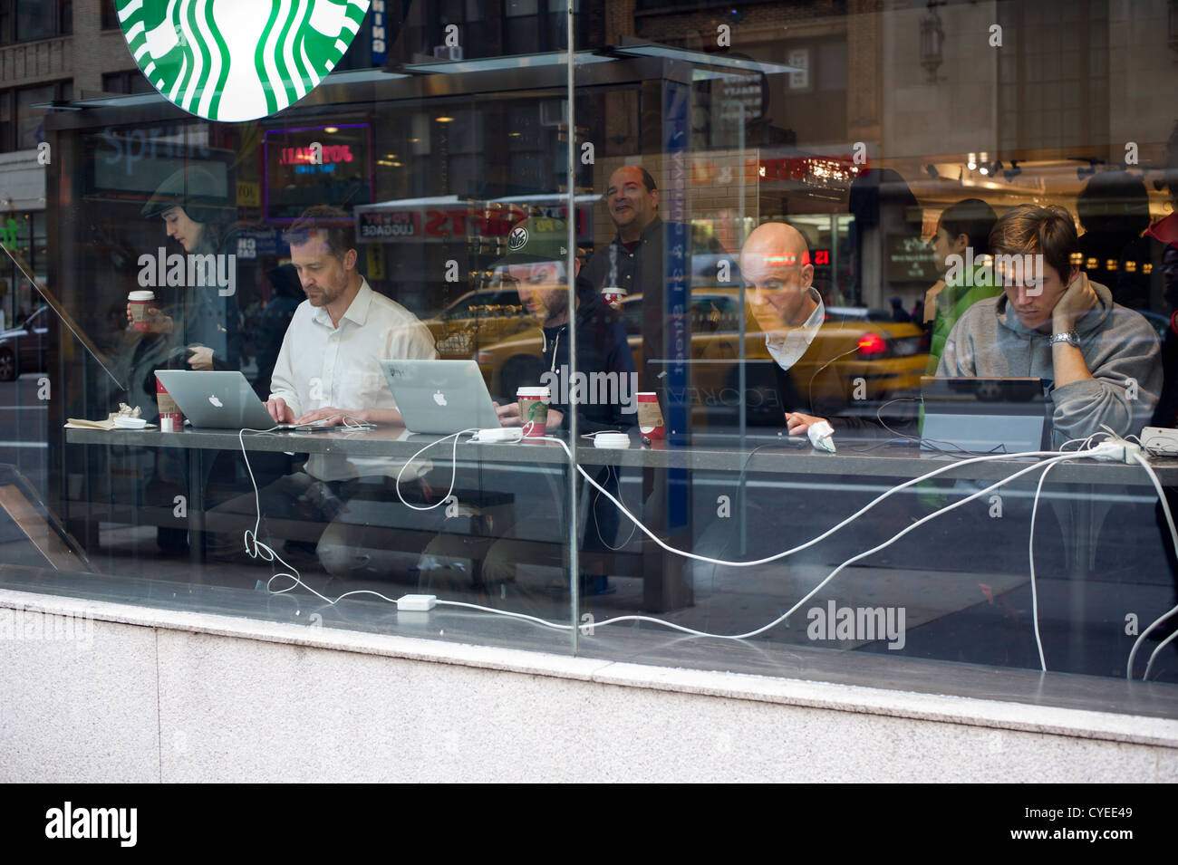 Le persone in carica i propri laptop in un Starbucks Coffee shop vicino Penn Station a Midtown a New York Foto Stock