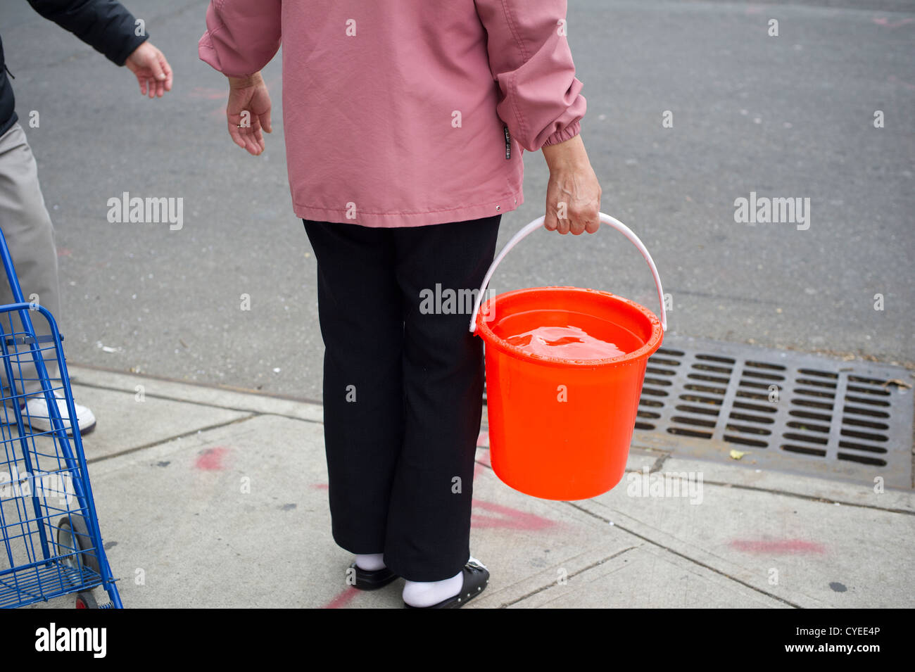 Un residente senza alimentazione dall uragano Sandy porta un secchio di acqua per cucinare e lavare con servizi igienici e a Chinatown Foto Stock