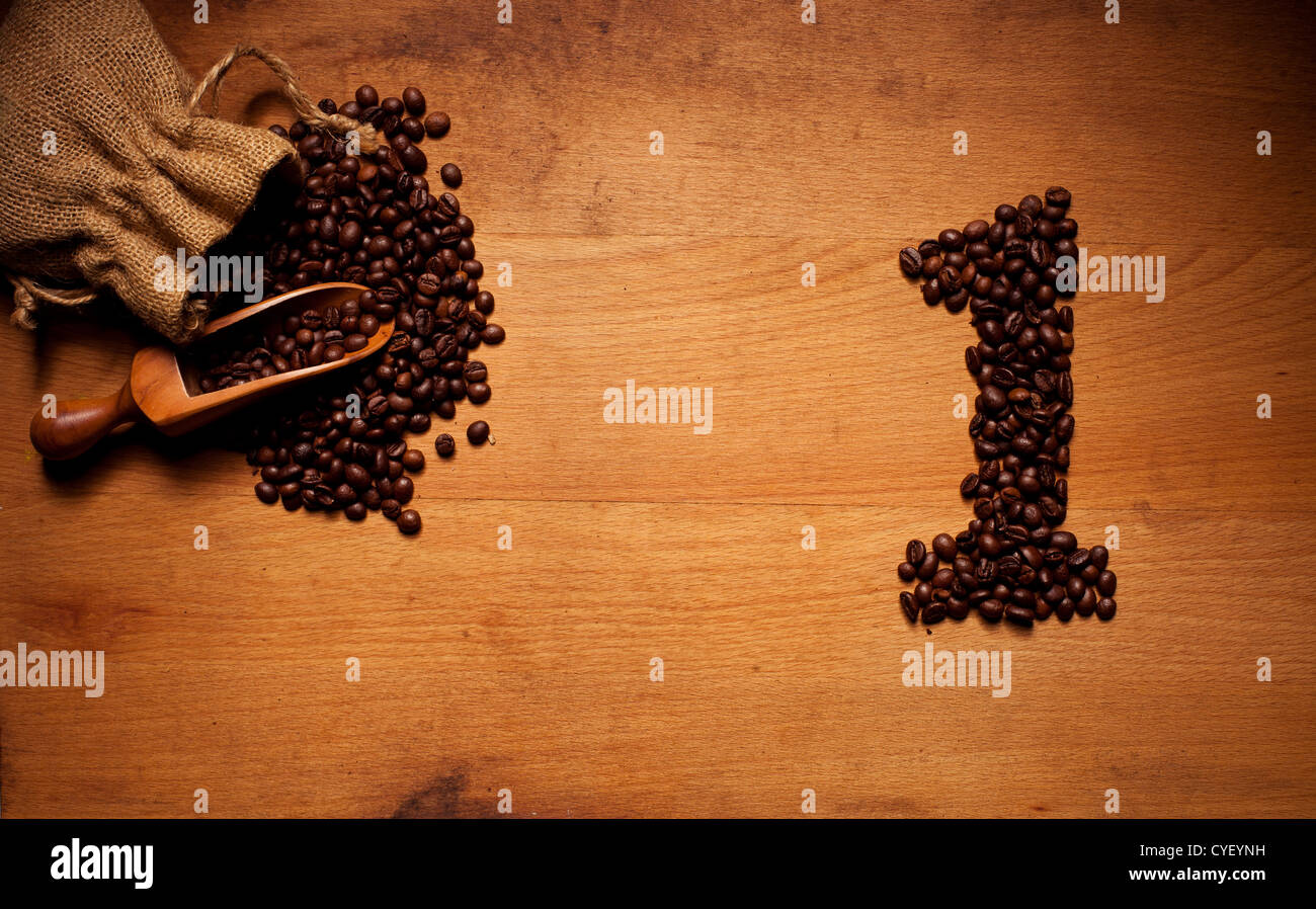 Appena il caffè torrefatto in grani la fuoriuscita di un Hessian sacco su una superficie in legno con un numero 1 Disposizione in grani Foto Stock