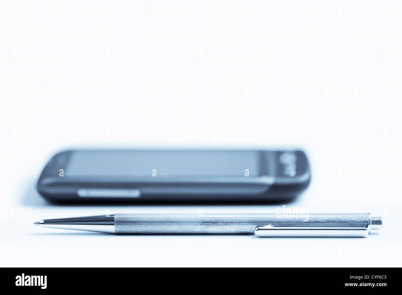 Una penna e un telefono cellulare sul tavolo, focus sulla penna. Foto Stock