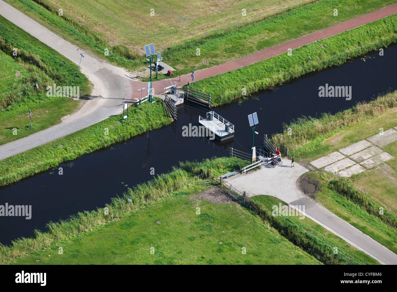 I Paesi Bassi, Eemnes. I ciclisti giovane fune di rimorchio di traghetto passeggeri a croce piccolo canale. Antenna. Foto Stock