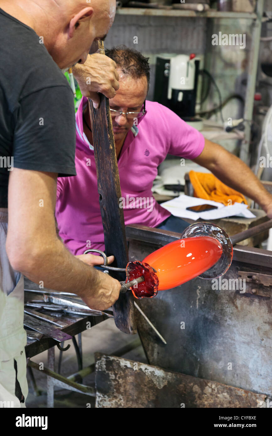 Due lavoratori in una fabbrica di vetro di Murano lavorando su un pezzo di vetro di Murano Foto Stock