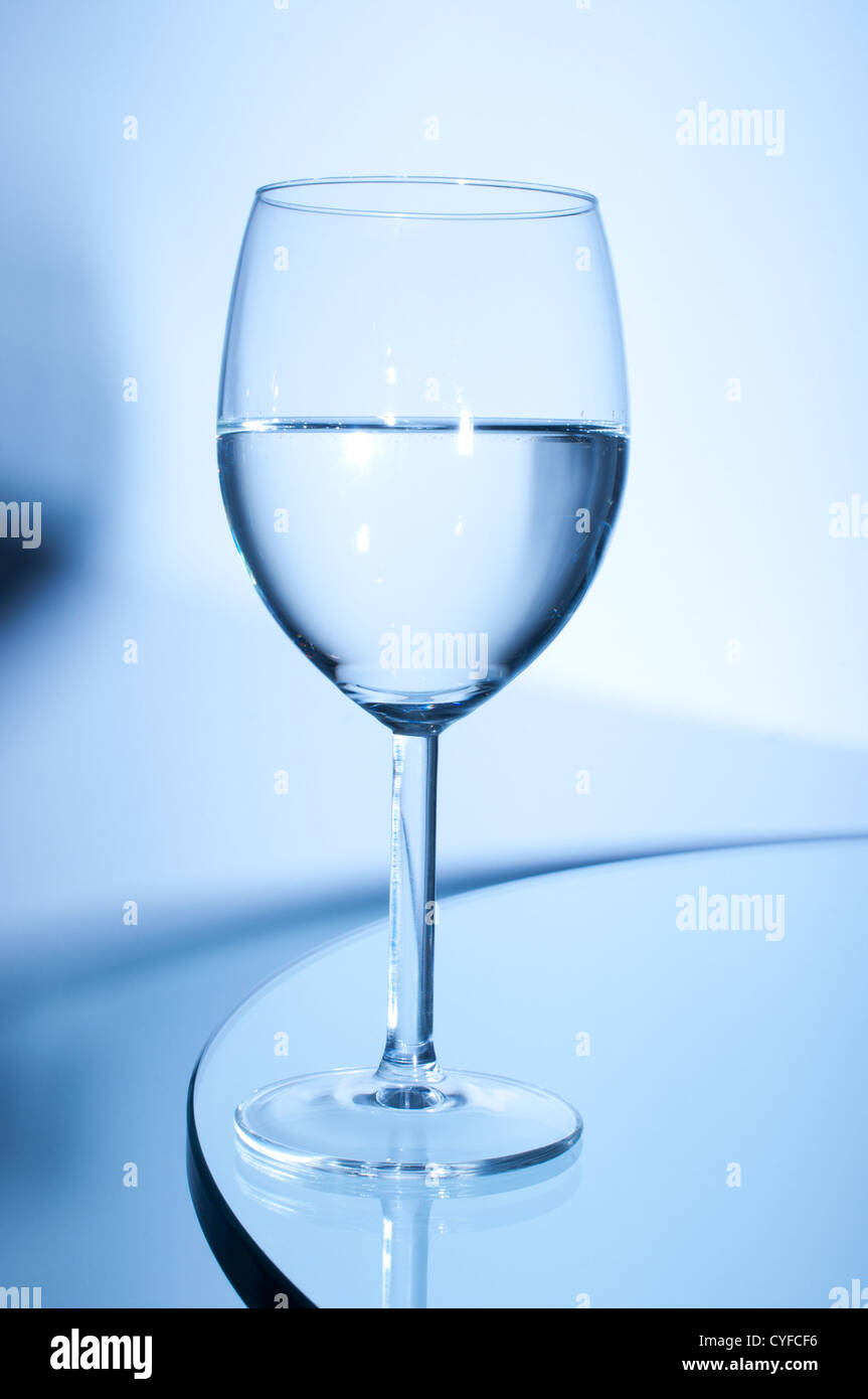 Bicchiere di vino bianco sul tavolo su sfondo blu Foto Stock