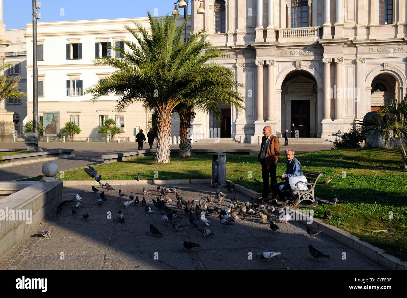 Gli uomini piccioni di alimentazione posizionato al di fuori del Pontificio Santuario della Beata Vergine del Rosario di Pompei, Italia Foto Stock