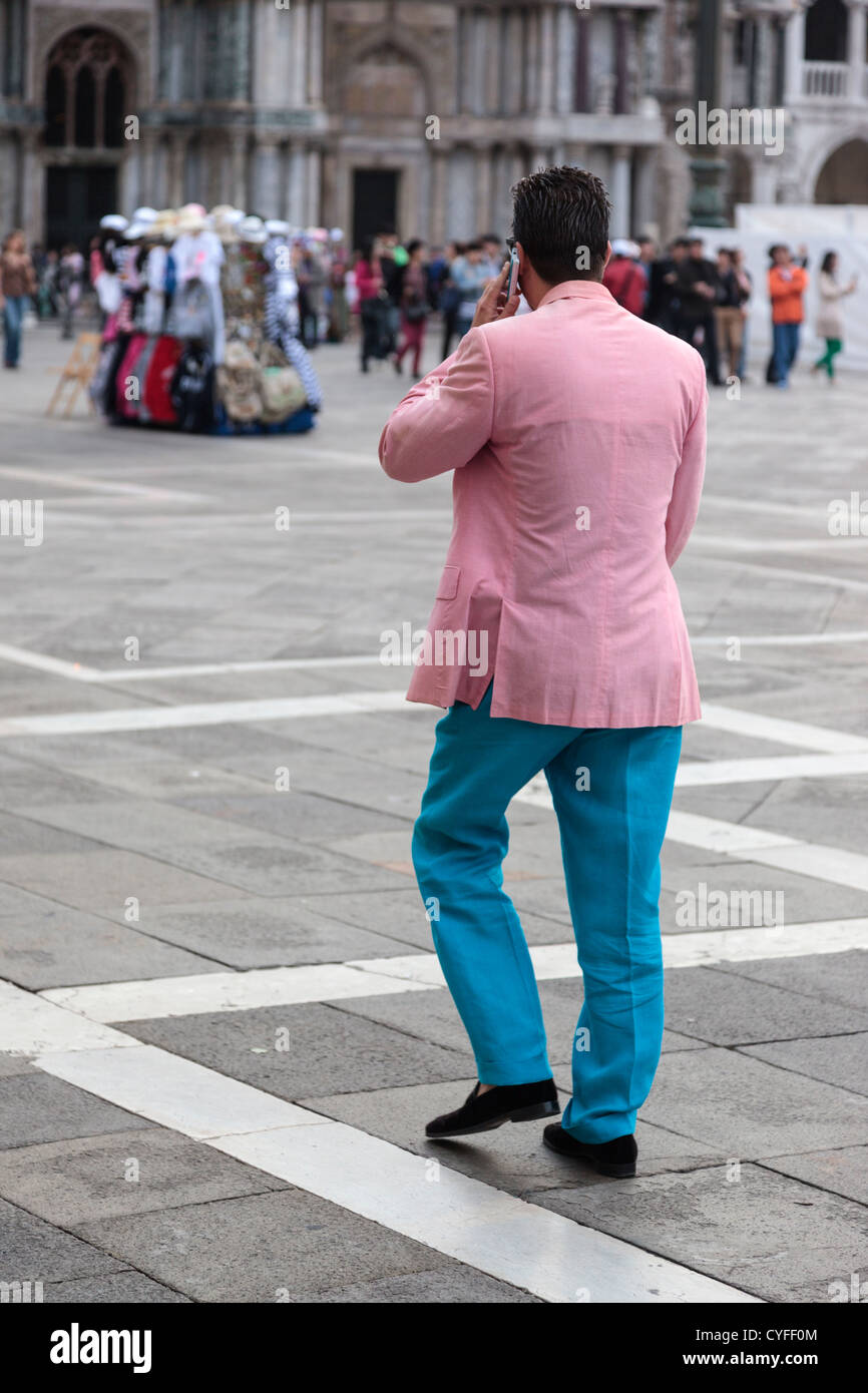 Italiano elegante uomo vestito in camicia rosa e turchese pantaloni  camminando in Piazza San Marco a Venezia parlando al cellulare Foto stock -  Alamy