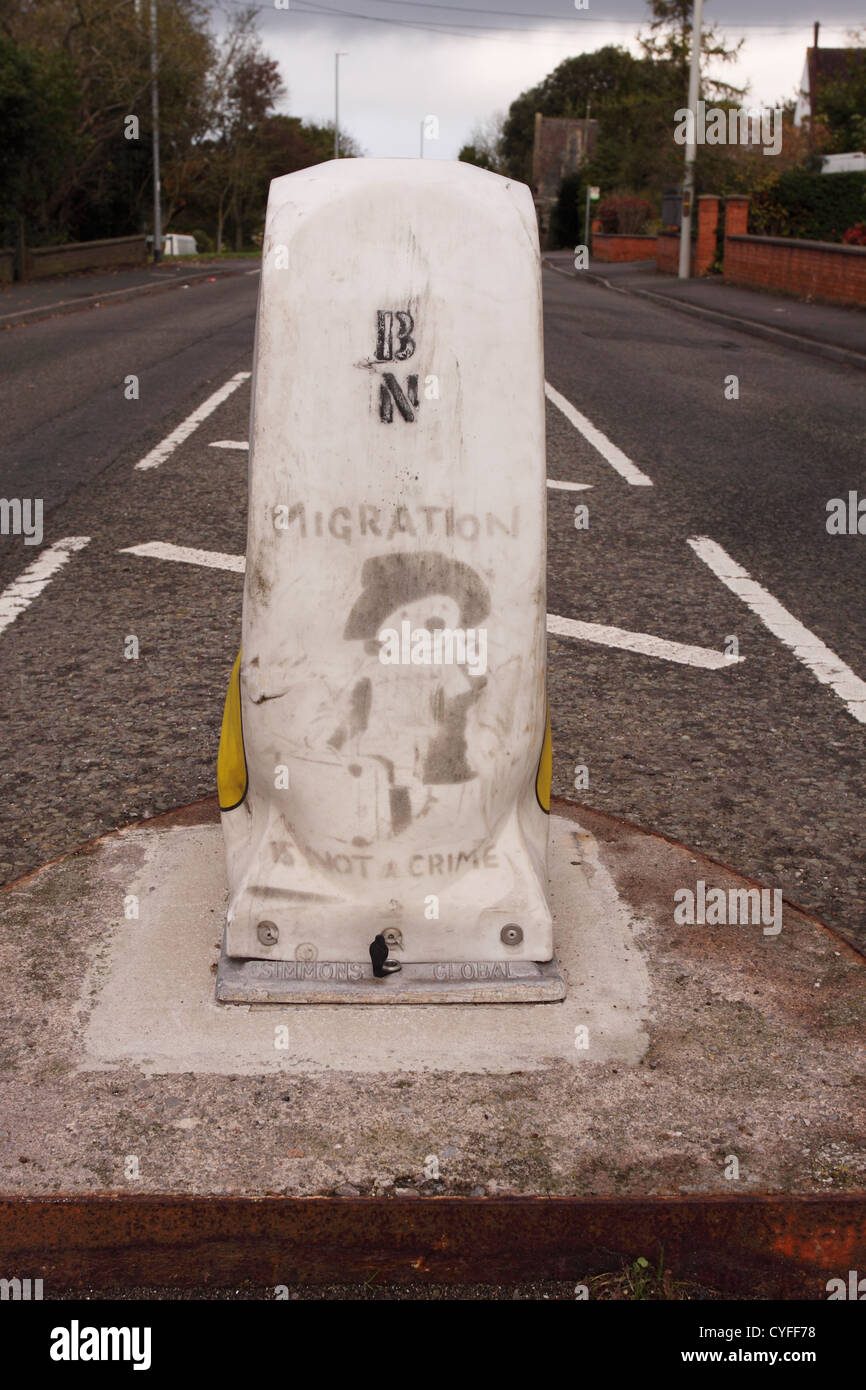 Banksy la migrazione non è un crimine stencil arte su un traffico stradale bollard in Glastonbury Somerset REGNO UNITO Foto Stock