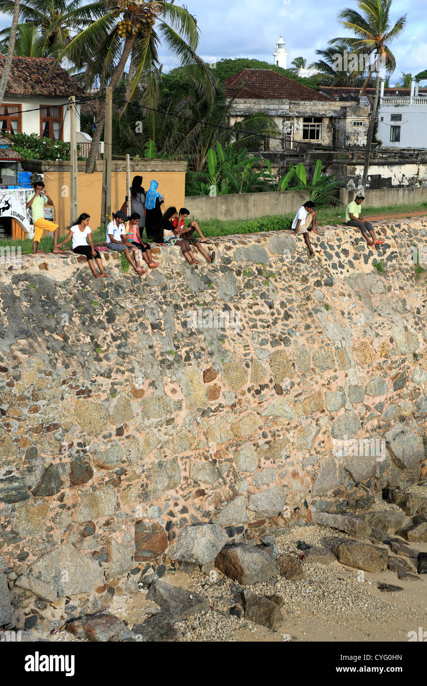 I giovani seduti sulla parete esterna Forte Galle nello Sri Lanka. Foto Stock