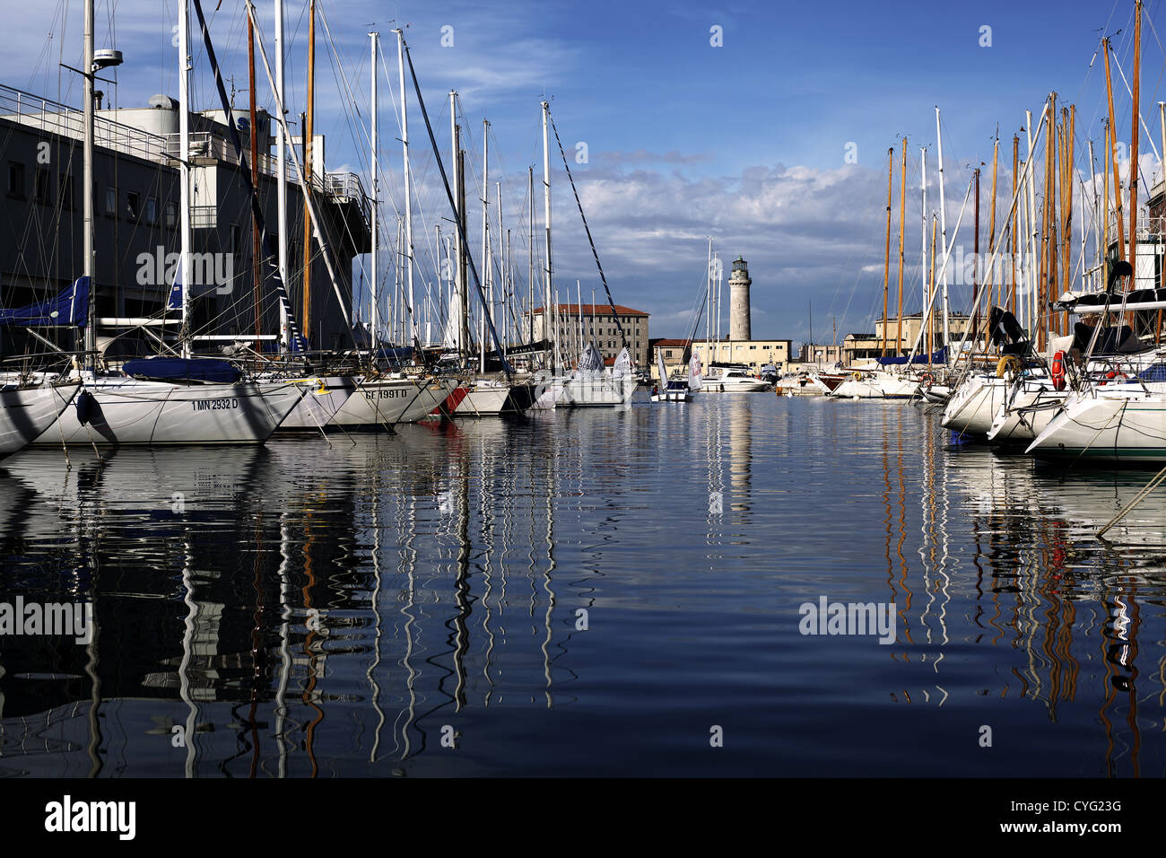 Vista di Trieste con molte barche a vela e i loro riflessi e faro al centro. Foto Stock