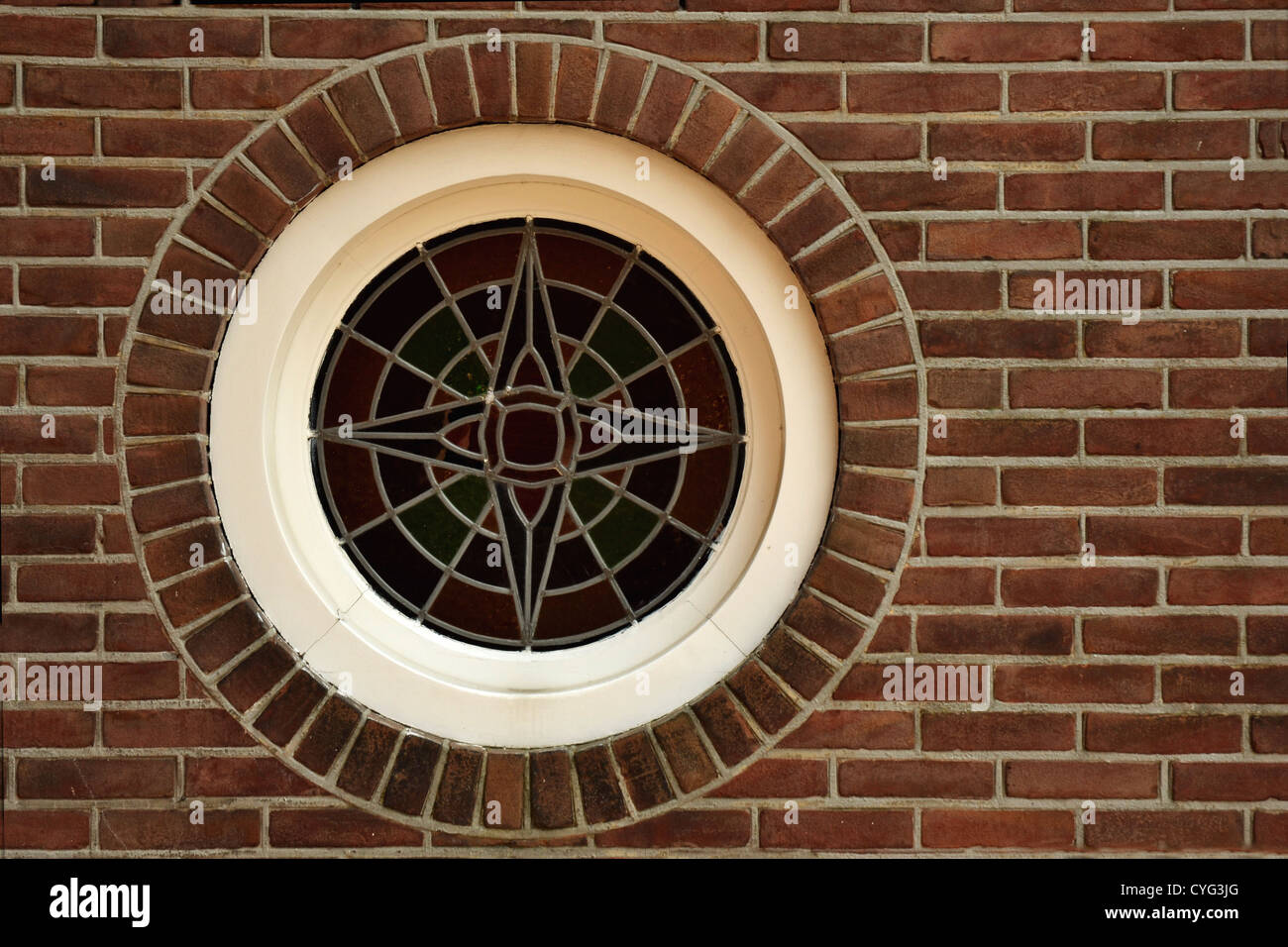 Round vetro piombato window set in rosso e parete di mattoni Foto Stock