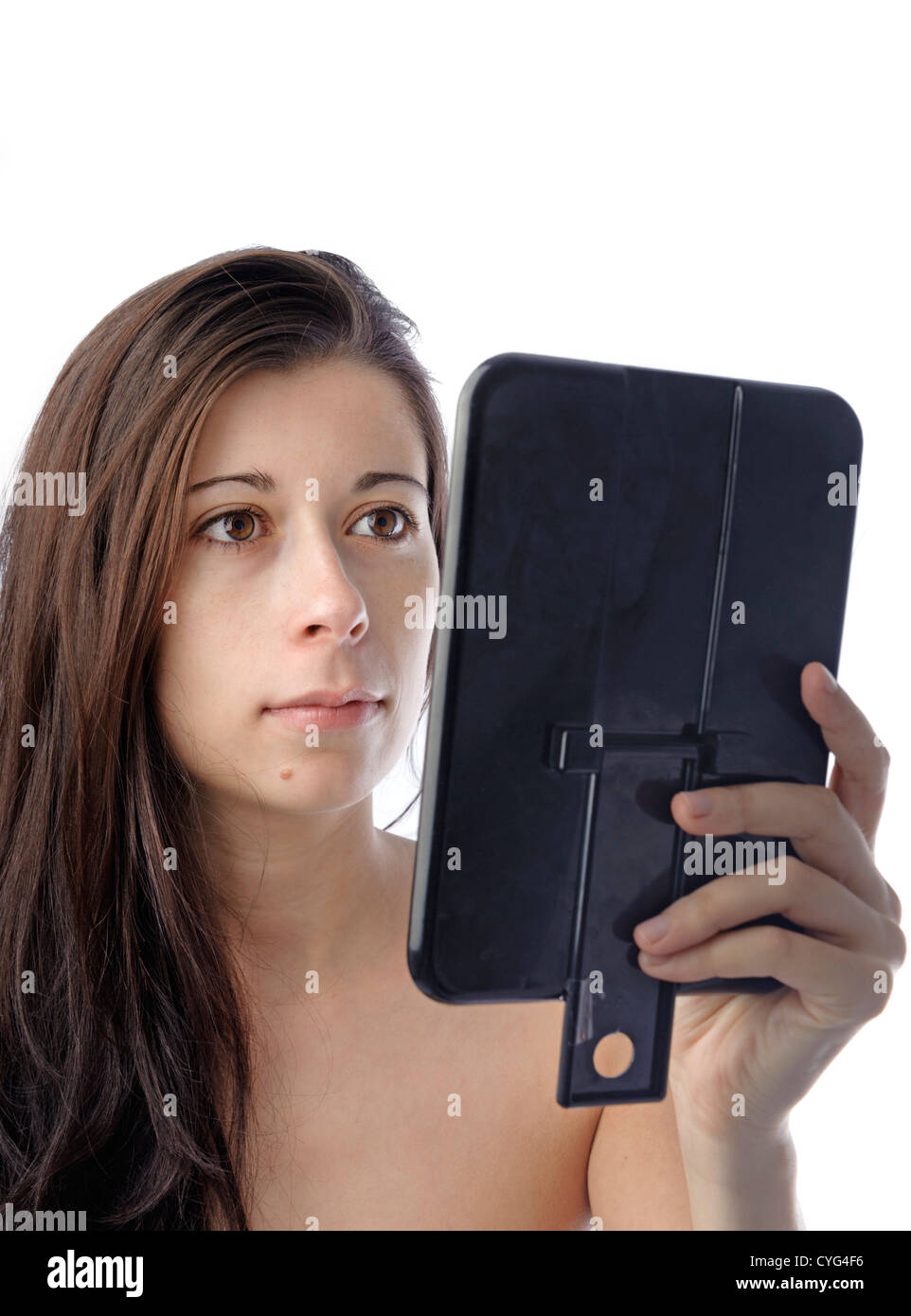 Giovane donna guardando il suo volto in uno specchio Foto Stock