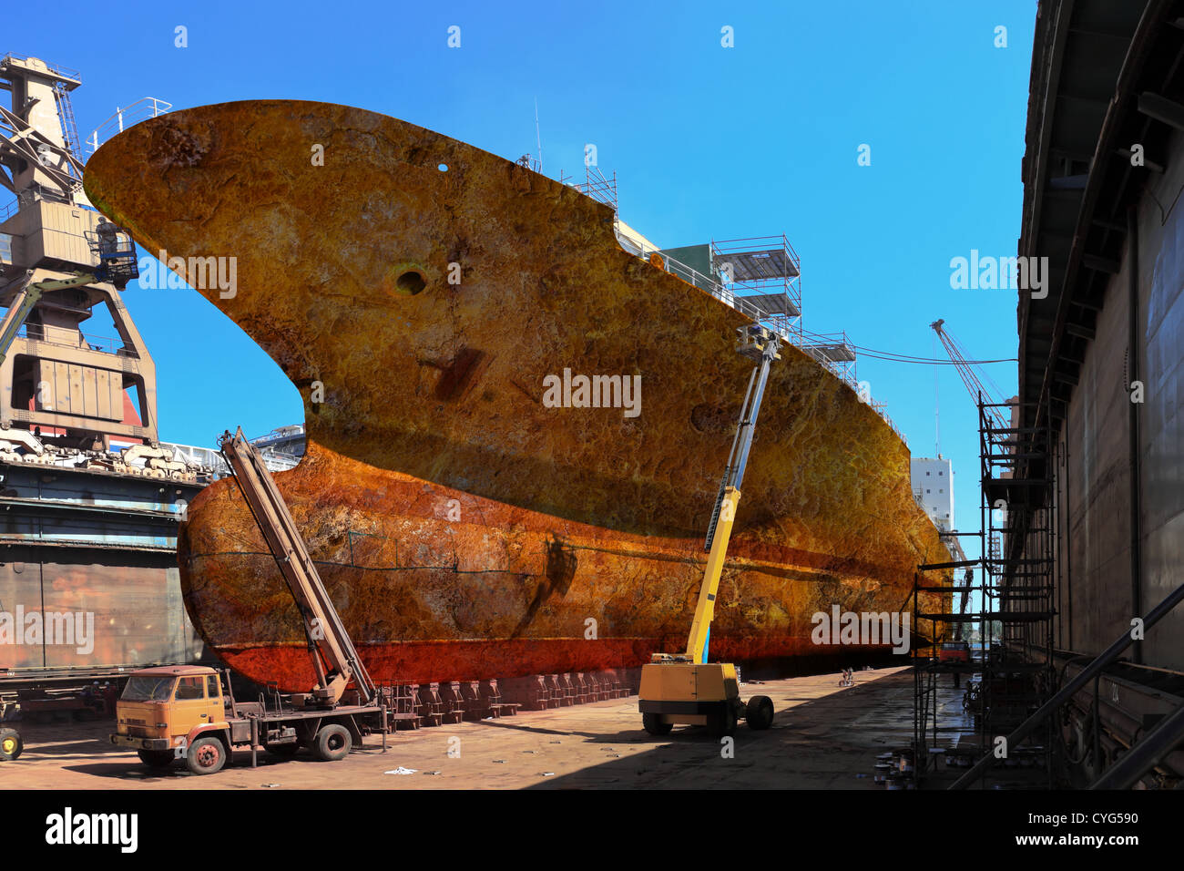 Lavoratori sabbiatura una grande nave da carico da ruggine e corrosione. Foto Stock