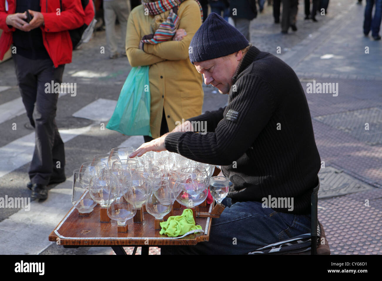 Uomo di mezza età di riproduzione di musica sull'arpa di vetro bicchieri di vino con quantità di acqua il mercato di El Rastro Madrid Spagna Europa Foto Stock